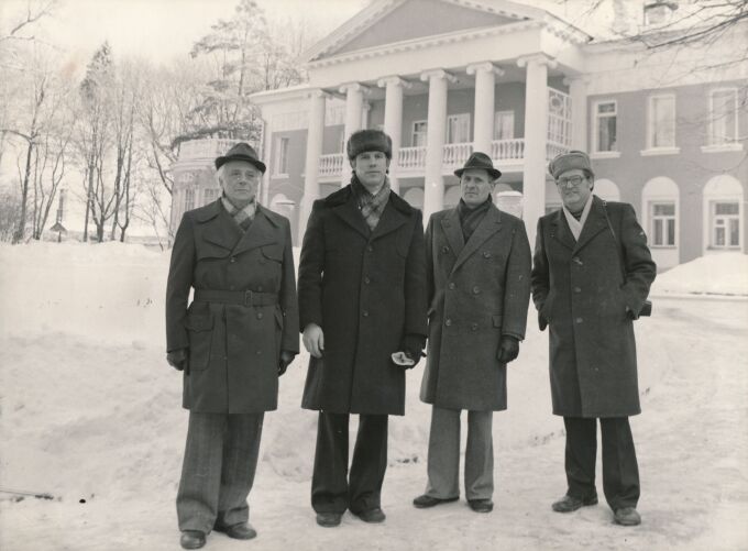 schwarz-weiß Foto von vier Männern im Schnee vor einer Villa