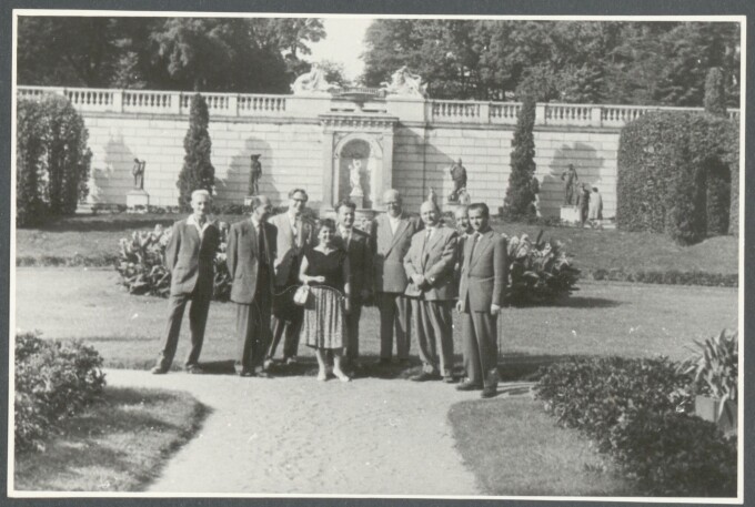 schwarz-weiß Foto einer Gruppe von acht Männern und einer Frau in prachtvollen Garten