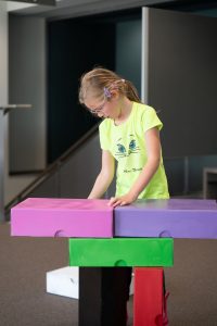 Ein Kind baut einen Turm aus bunten Archivkartons